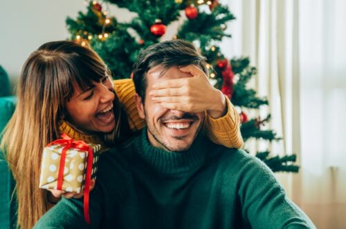 Image Text: woman giving man a present, maybe the gift of a new smile this New year, cosmetic dentistry