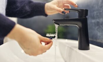 Teenage girl is washing transparent dental aligner in the bathroom Image Text: woman rinsing invisalign aligners for Invisalign care