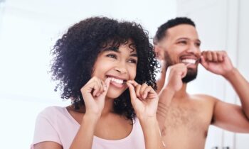 Image Text: couple flossing their teeth to care for dental implants